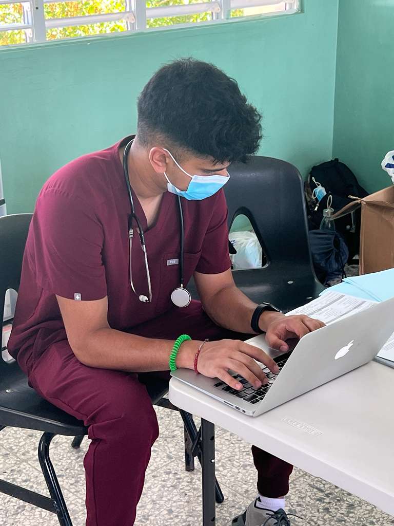 Global Health Leaders medical student participating in the 1:1 Medical Research Mentorship program, analyzing research data and preparing reports on a laptop in a clinical setting.