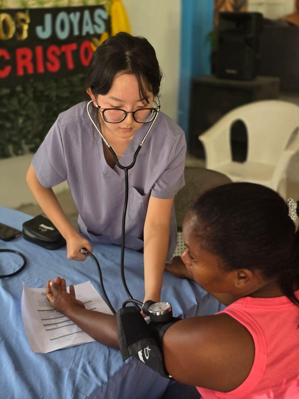 Global Health Leaders medical student measuring a patient’s blood pressure during a mentorship clinic, gaining real-world experience in global health research and care.
