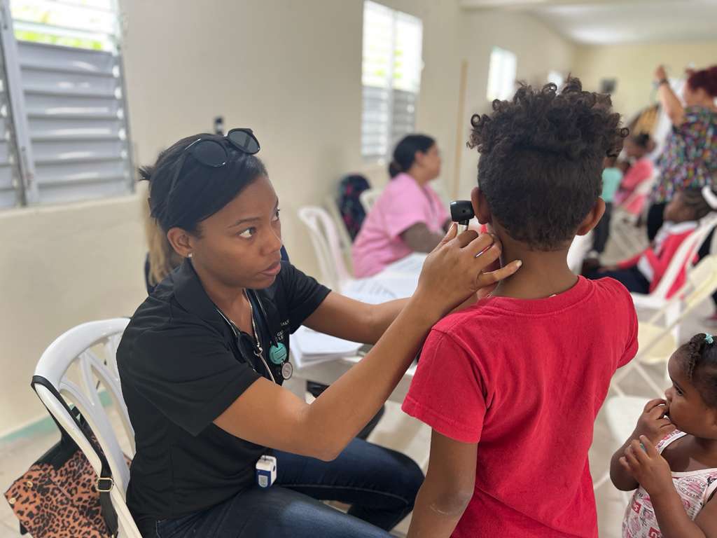 Global Health Leaders medical trainee mentoring session with a child patient in a community clinic, providing hands-on experience in global health and clinical research.